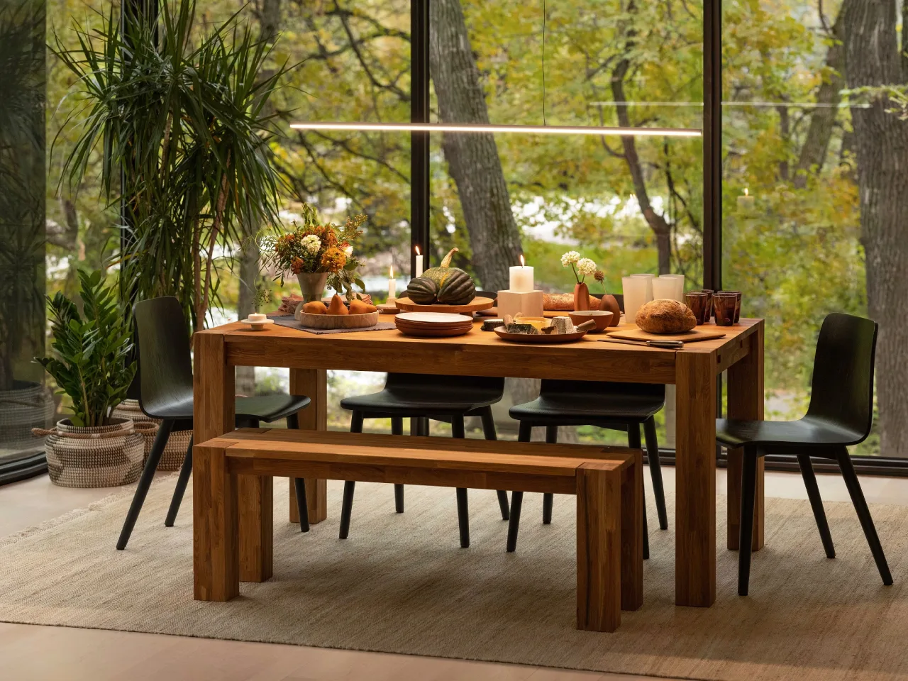 Rustic farmhouse dining area featuring a massive solid wood harvest table and exposed stone walls—traditional retreat design in Siruvani.
