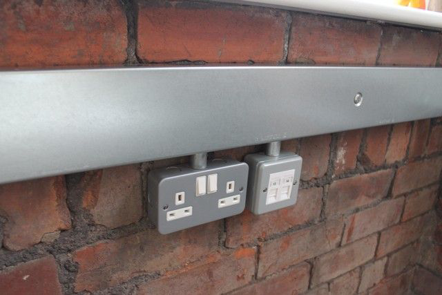 Heavy-duty industrial metal-clad electrical switches on an exposed brick wall—durable farmhouse utility design in Coimbatore.